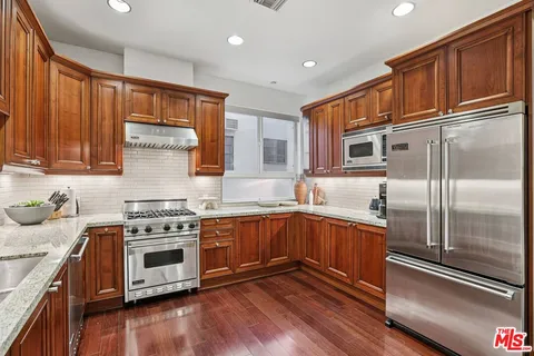 a kitchen with stainless steel appliances granite countertop a stove a sink and a refrigerator