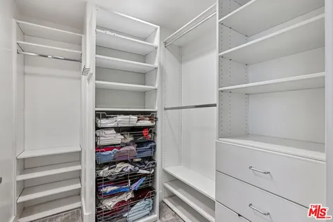 a view of walk in closet with clothes and shoes
