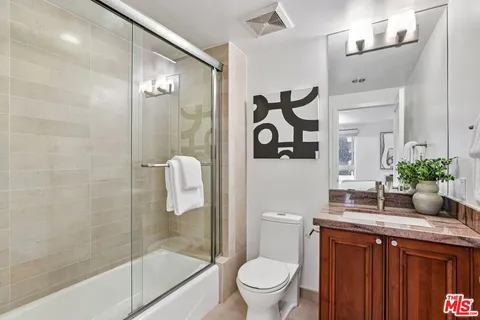 a bathroom with a granite countertop sink a toilet and shower