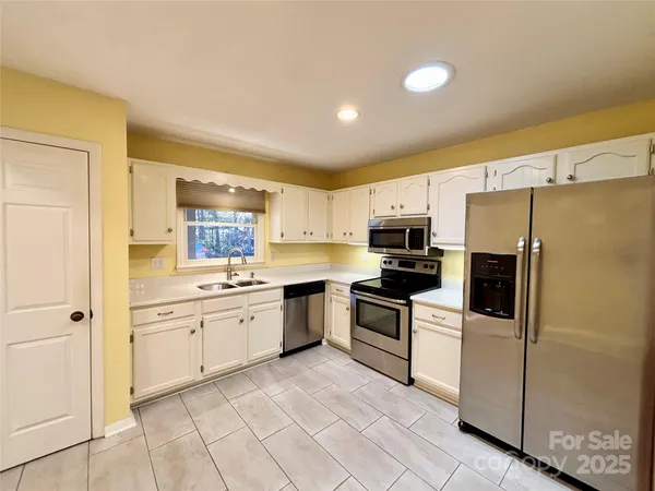 a large kitchen with cabinets stainless steel appliances and a window