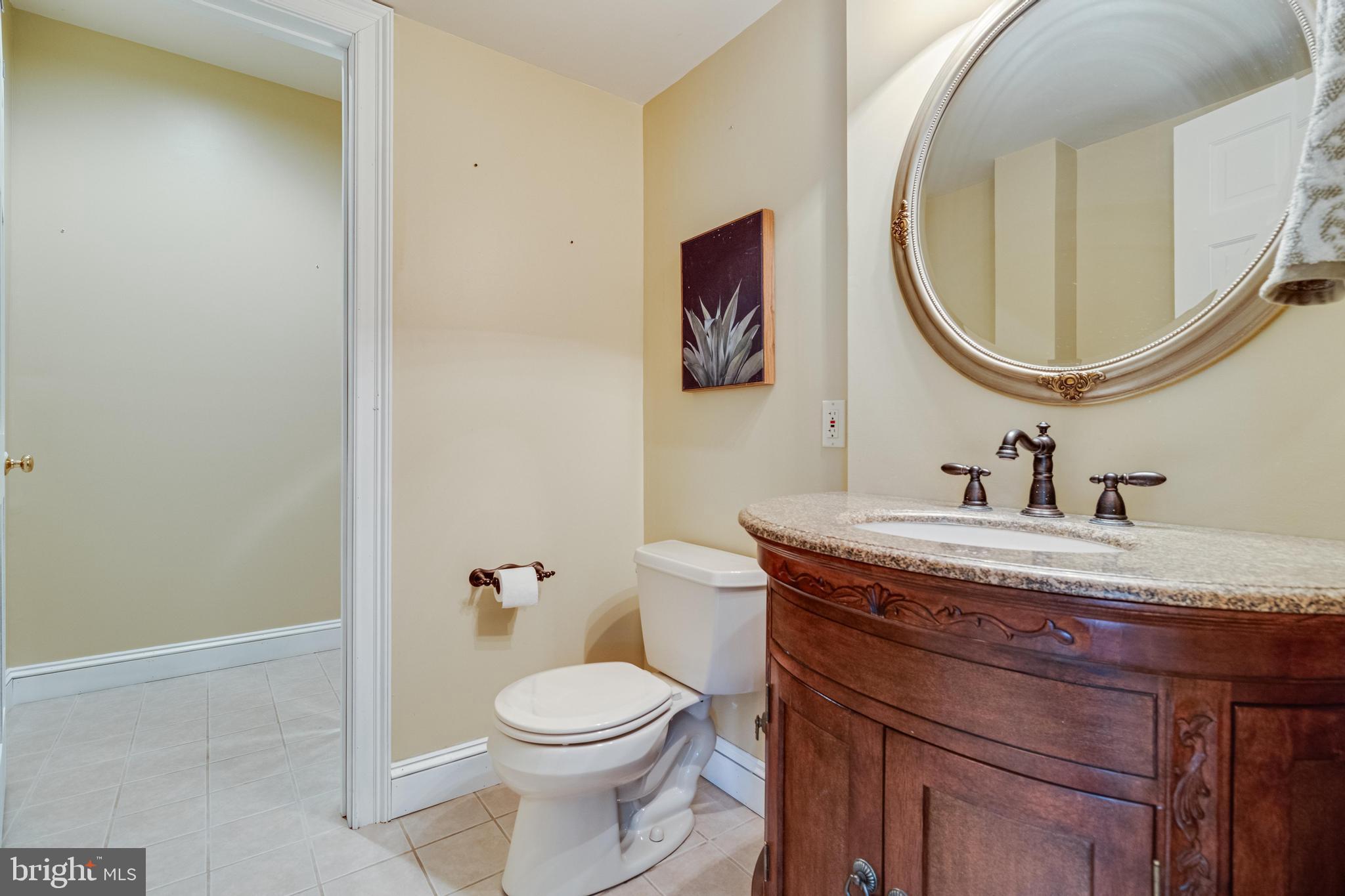 99 Hummingbird Court Dunkirk, MD 20754 - Photo 58 of 84 a bathroom with a granite countertop toilet a sink and a mirror
