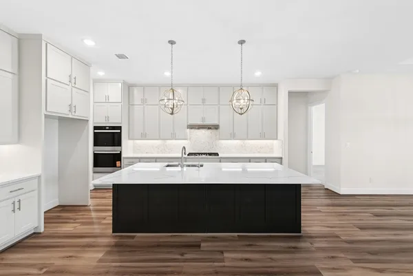 a kitchen with kitchen island granite countertop a sink a counter space and cabinets