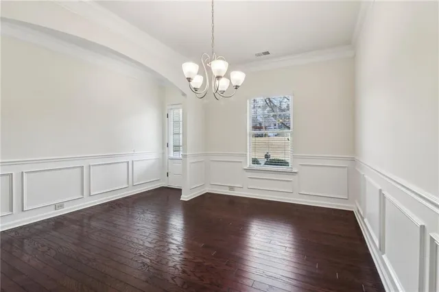 a view of an empty room with wooden floor and windows