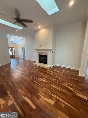 an empty room with wooden floor fireplace and windows