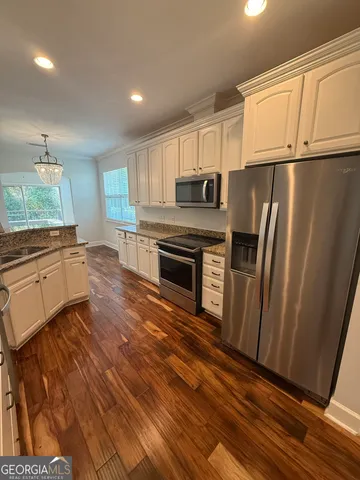 a kitchen with granite countertop a refrigerator and a stove top oven