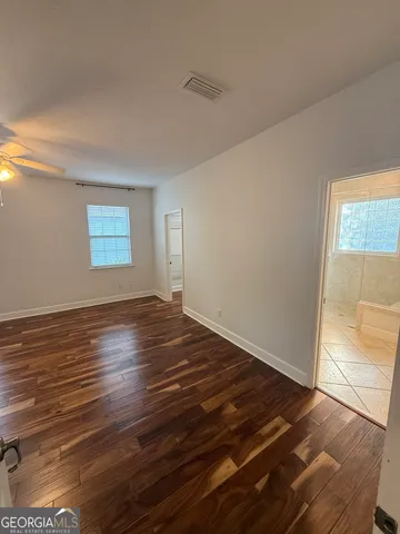 an empty room with wooden floor and windows