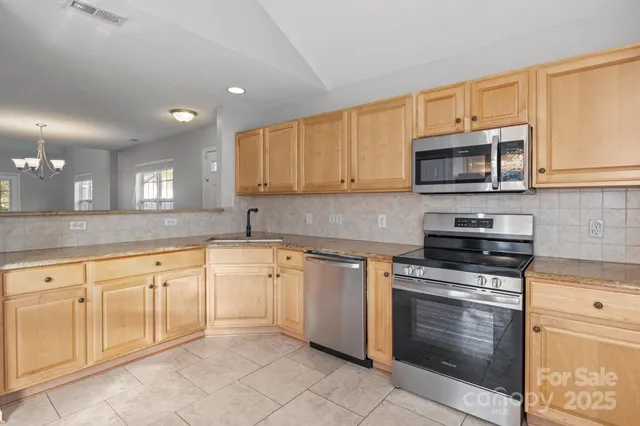 a kitchen with granite countertop a stove top oven microwave and cabinets