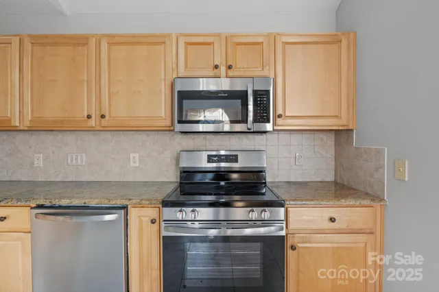 a kitchen with granite countertop cabinets stainless steel appliances and a counter space