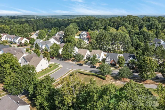 an aerial view of residential houses with outdoor space and trees
