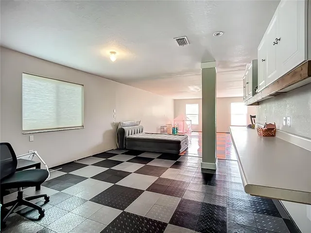 a living room with a black white checkered floor with a gaming machine and appliances