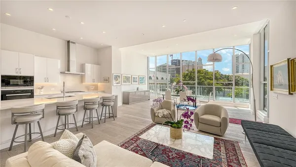 a living room with furniture large windows and wooden floor