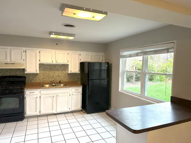 a kitchen with a refrigerator a stove top oven and a window