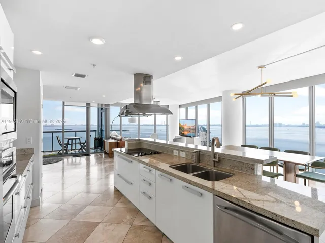 a large white kitchen with a large window and stainless steel appliances