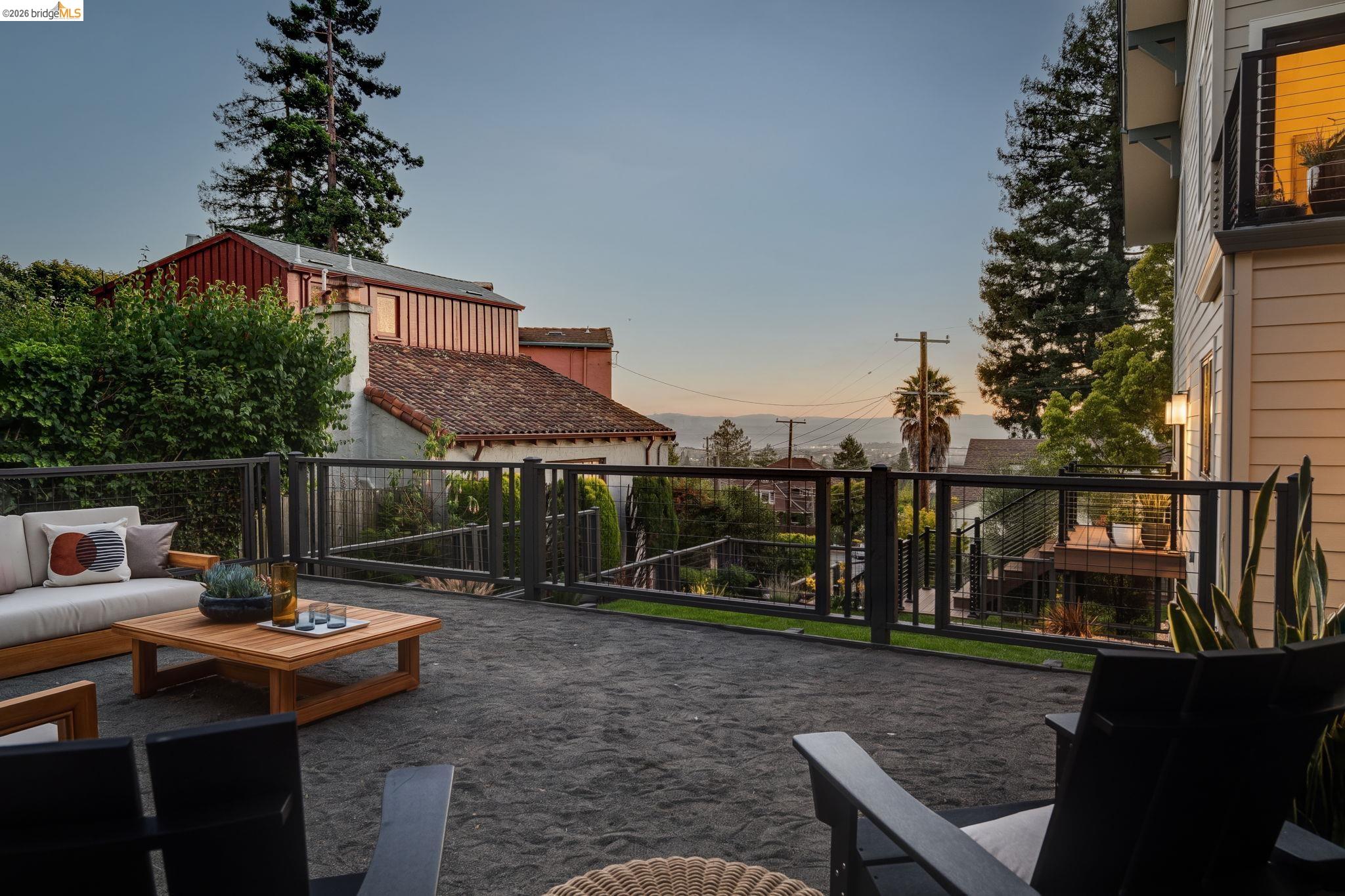 1409 Scenic Avenue Berkeley, CA 94708 - Photo 15 of 28 Spacious outdoor patio area featuring a gravel surface, dark metal railings, and a residential backdrop