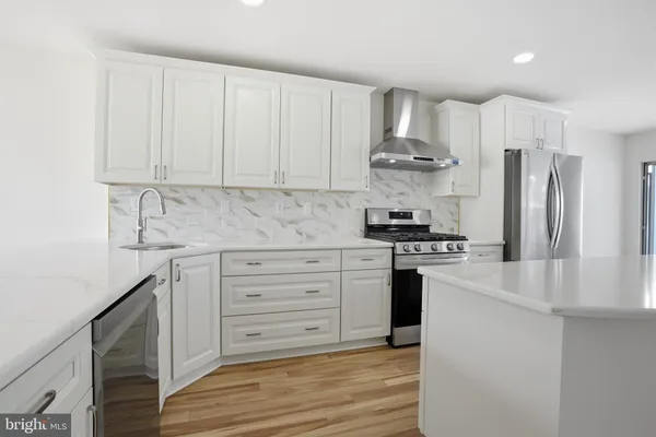 a kitchen with stainless steel appliances white cabinets and a stove top oven