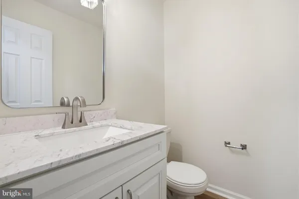 a bathroom with a granite countertop toilet sink and mirror