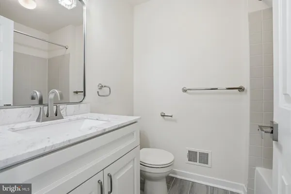 a bathroom with a granite countertop sink toilet and mirror