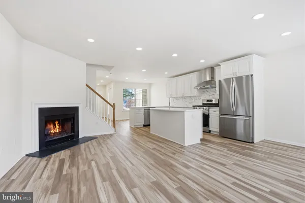 a open kitchen with kitchen island wooden floors appliances and cabinets