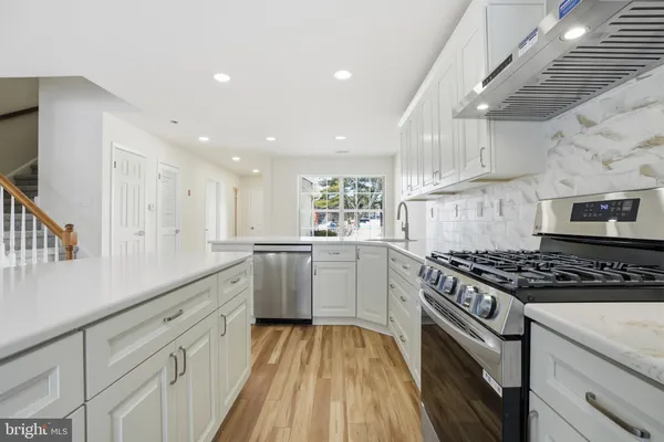a kitchen with white cabinets stove and sink
