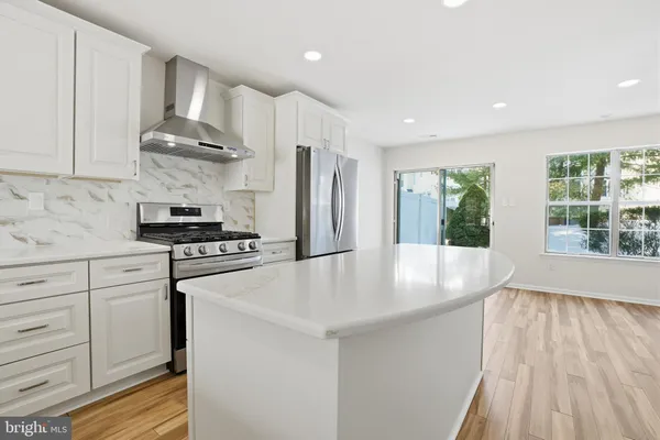 a kitchen with stainless steel appliances granite countertop a refrigerator a sink and white cabinets