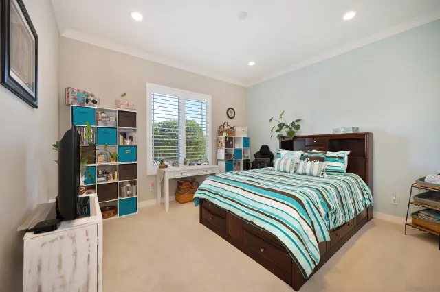a bedroom with a bed a large window and book shelf