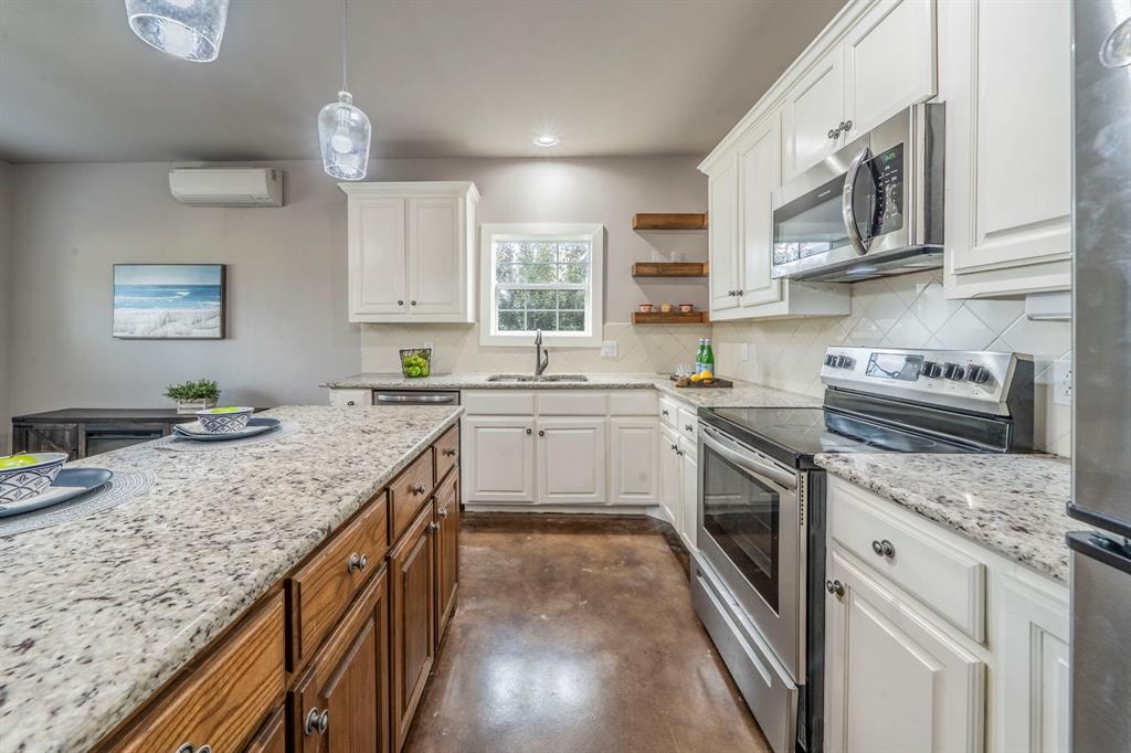 1992 Bledsoe Road Gunter, TX 75058 - Photo 26 of 40 a kitchen with stainless steel appliances granite countertop a sink stove and cabinets