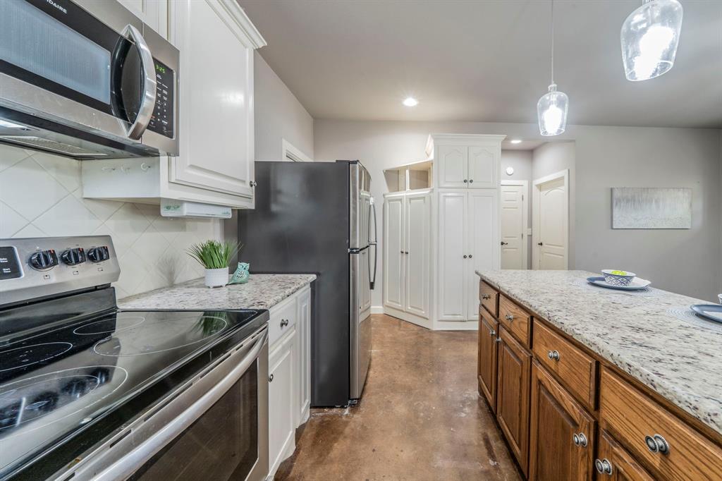 1992 Bledsoe Road Gunter, TX 75058 - Photo 27 of 40 a kitchen with stainless steel appliances granite countertop a sink stove and refrigerator