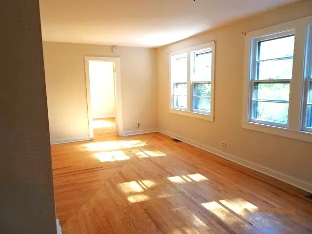 a view of an empty room with wooden floor and a window