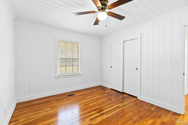 a view of an empty room with window and wooden floor