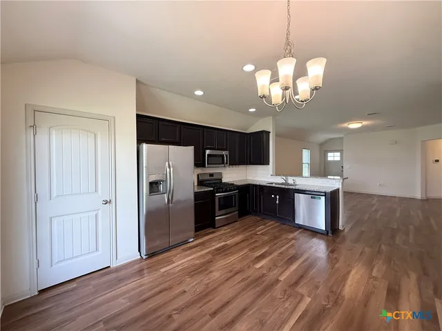 a kitchen with stainless steel appliances granite countertop a refrigerator a sink dishwasher a kitchen island with wooden floor