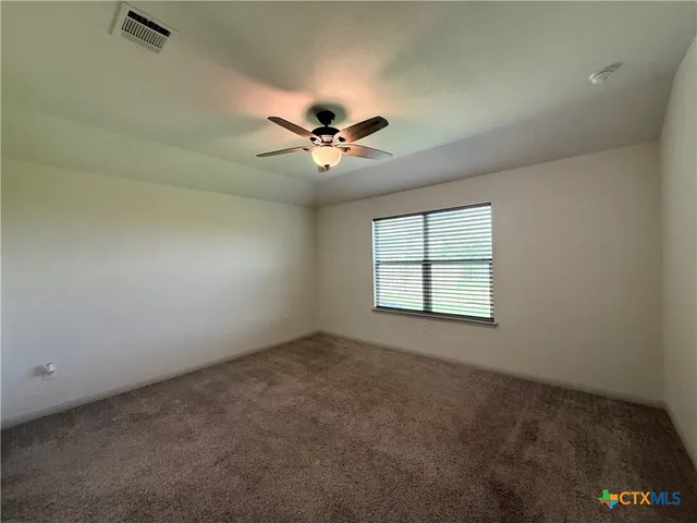 an empty room with a chandelier fan and windows