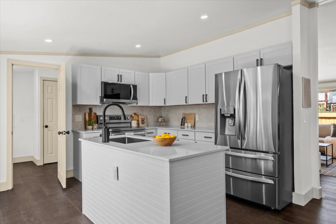Kitchen featuring stainless steel appliances, light countertops, tasteful backsplash, dark wood-style flooring, and recessed lighting