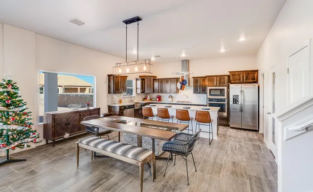 a kitchen with stainless steel appliances a refrigerator stove microwave and chairs