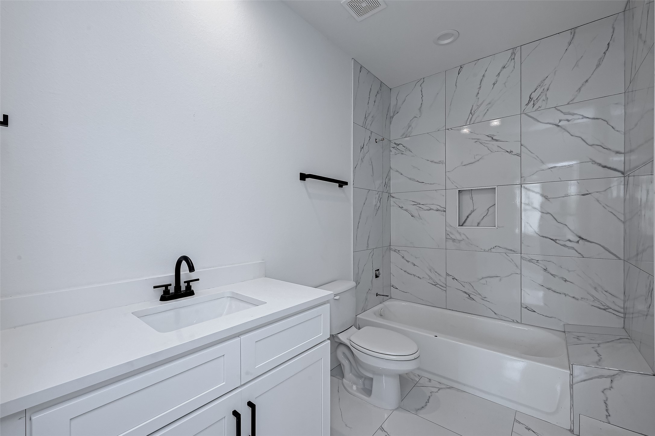 6032 Beall Street Houston, TX 77091 - Photo 26 of 26 A sleek secondary bath includes a deep soaking tub with striking tile surround, modern vanity, and matte black hardware for a clean, contemporary finish.