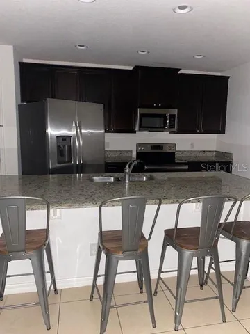 a kitchen with stainless steel appliances kitchen island granite countertop a stove top oven a sink with dining table and chairs