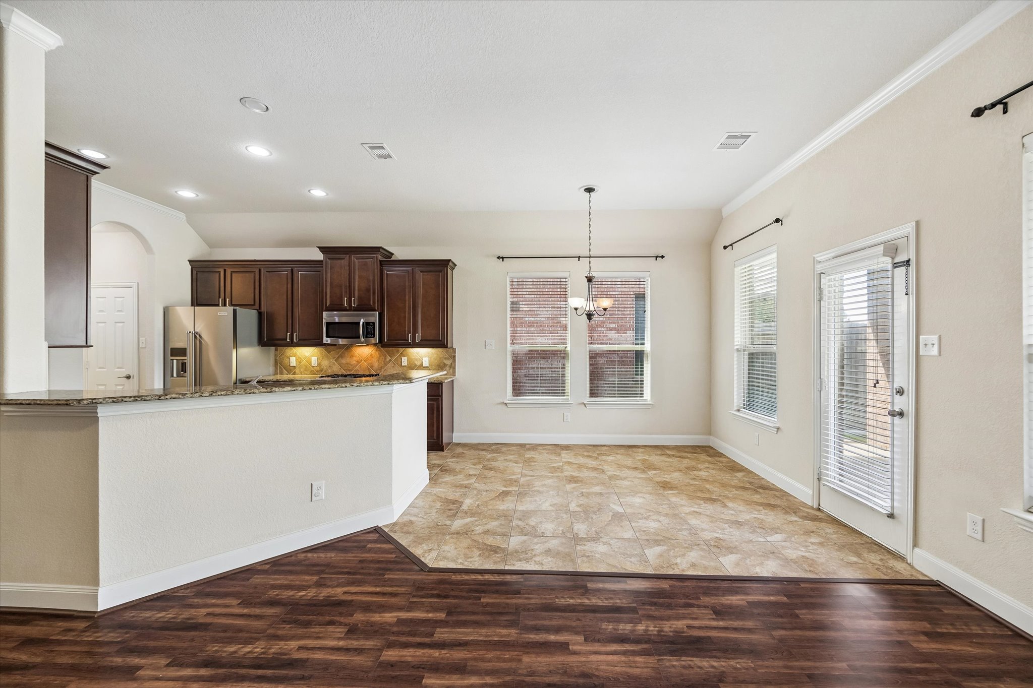 2214 Wembley Way Rosenberg, TX 77471 - Photo 14 of 35 Open-concept living area featuring a kitchen with dark wood cabinetry, stainless steel appliances, and a granite-style countertop