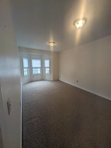 an empty room with windows and fireplace