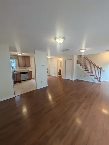 a view of a livingroom with wooden floor and a staircase