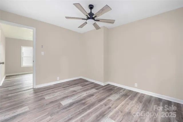 a view of an empty room with window and a chandelier fan