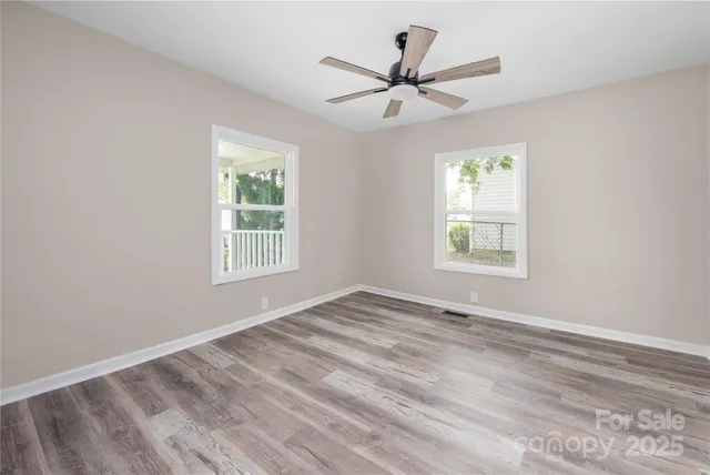 a view of a big room with wooden floor and windows