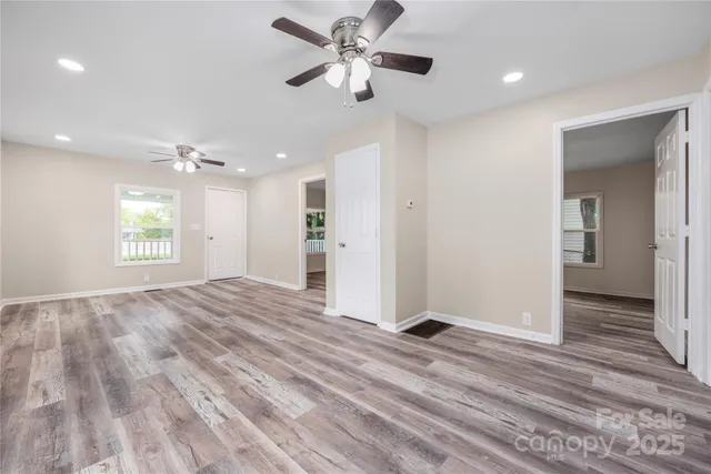 a view of an empty room with window and wooden floor