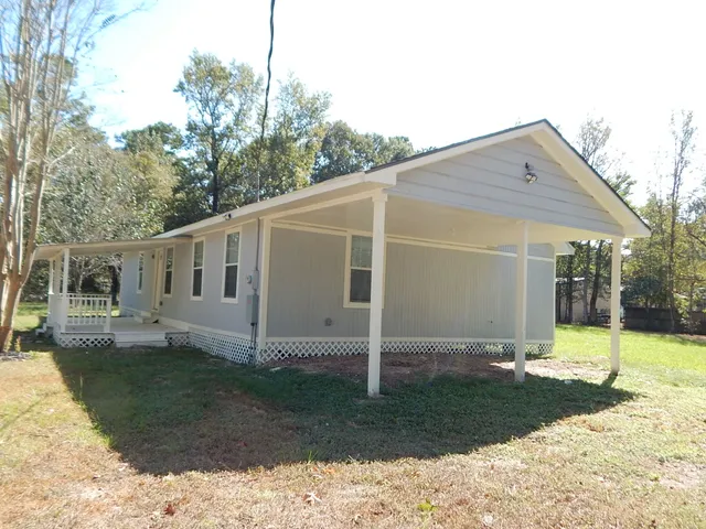 a view of a barn in the backyard with large tree