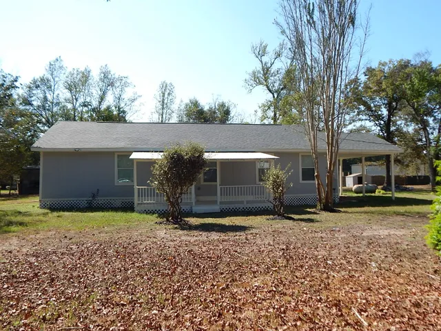 a view of a house with a yard and large tree