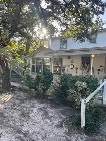 a front view of a house with plants and trees