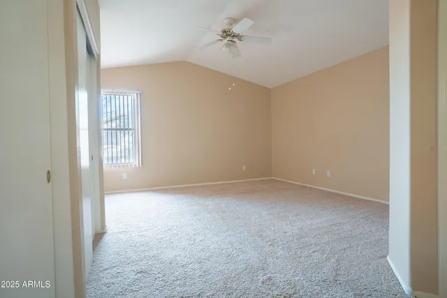 an empty room with windows and ceiling fan