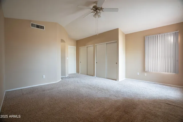 a view of a room with a ceiling fan and windows