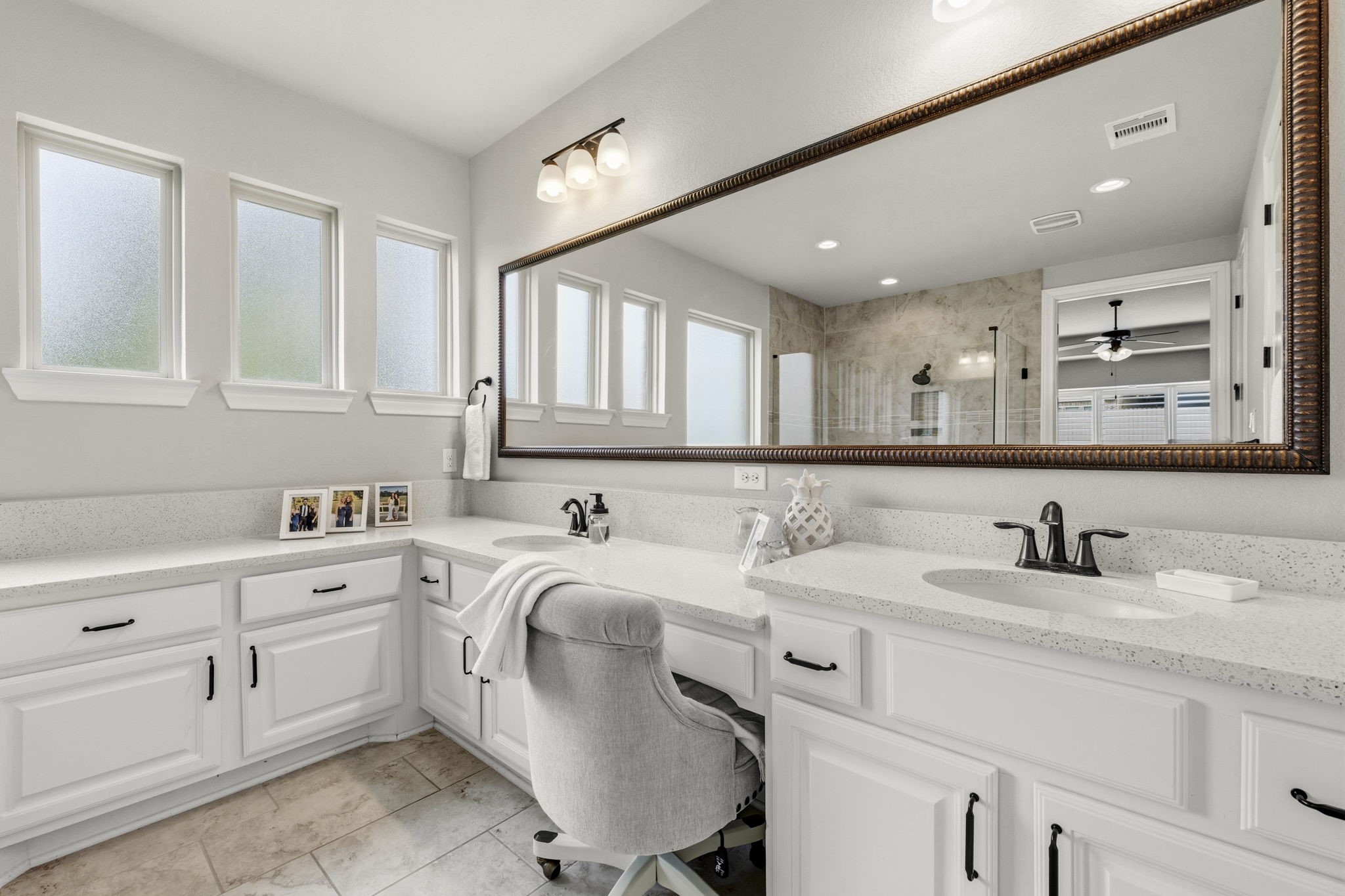 14012 Beartooth Bend Trail Conroe, TX 77384 - Photo 22 of 50 The spa-inspired primary bath features dual vanities thoughtfully positioned for enhanced space, functionality, and privacy. Rich custom cabinetry, sleek quartz countertops, oval undermount sinks, medicine cabinet, and an elegantly framed mirror create a refined and sophisticated aesthetic. A dedicated sit-down vanity offers the perfect space for daily pampering, while the elevated gentleman’s vanity adds both comfort and convenience for grooming and shaving.