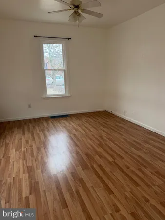 an empty room with wooden floor a ceiling fan and windows