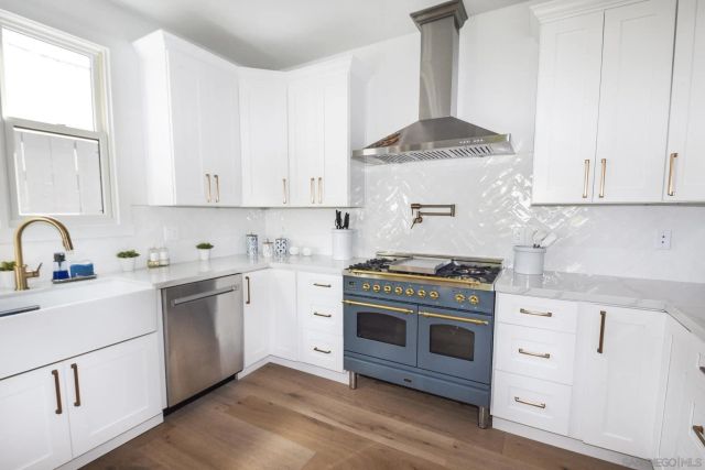 a kitchen with stainless steel appliances a stove a sink and white cabinets