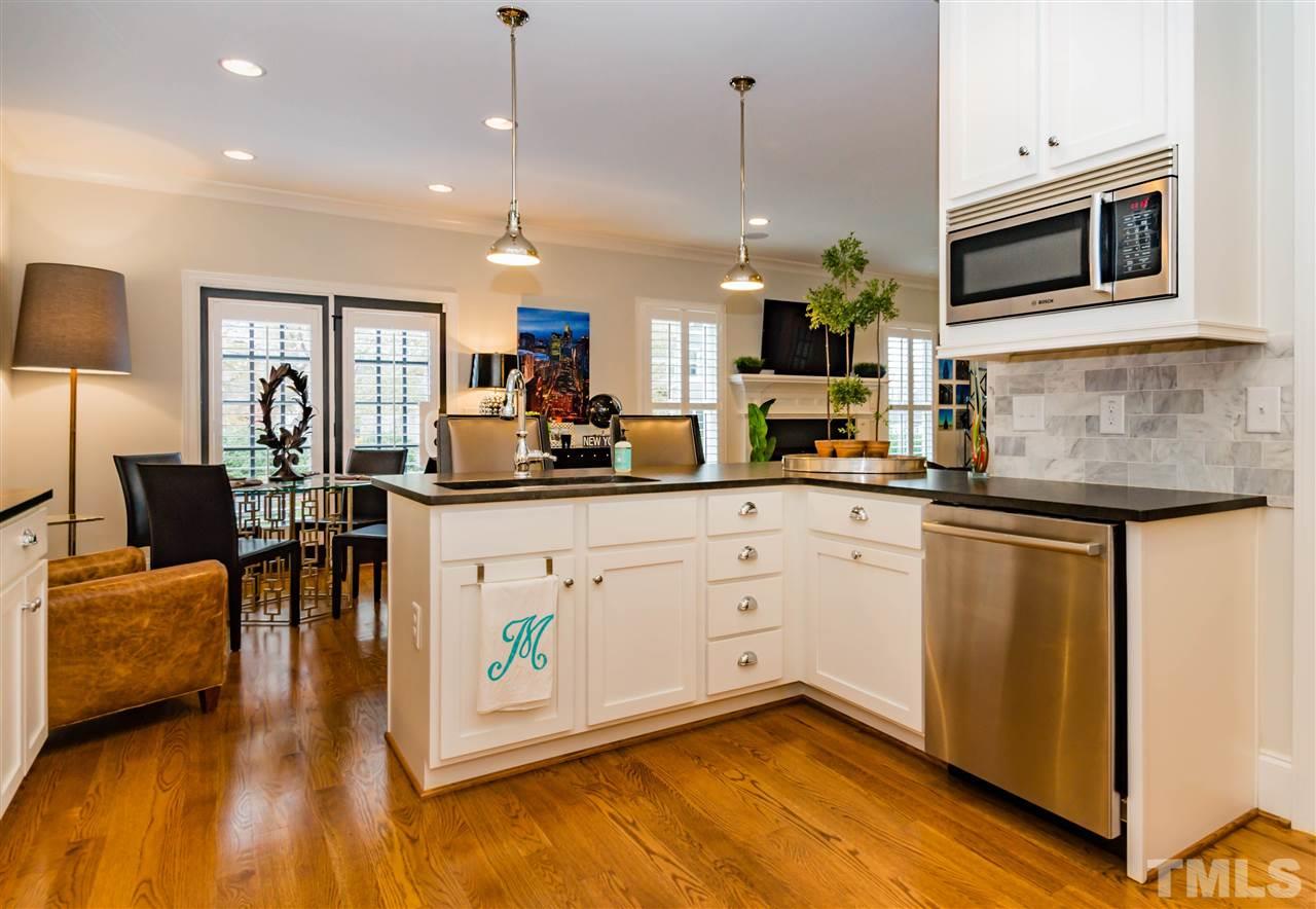 511 Mial Street Raleigh, NC 27608 - Photo 11 of 25 a kitchen with stainless steel appliances granite countertop a stove a sink a microwave a dining table and chairs with wooden floor